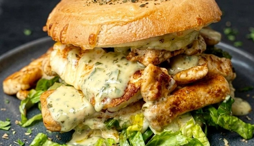 Toasted bagel with tzatziki sauce, melted cheese, lettuce, chicken gyros and halloumi, drizzled with more tzatziki sauce and